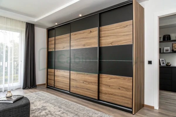 Modern wardrobe with bold black and woodgrain sliding doors, recessed lighting, and full-wall integration in a bright and airy bedroom setting.