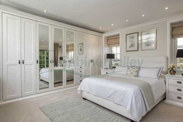 Wall-mounted hinged wardrobe in matte white with mirrored doors and clean molding details, adding brightness and visual depth.