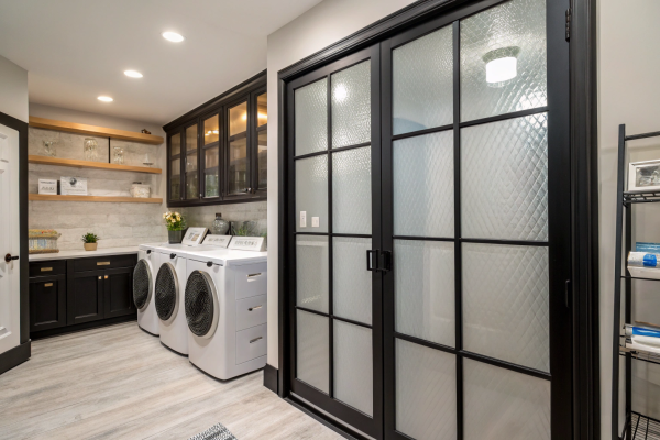Built-in laundry cabinetry with textured glass sliding doors and matte black finishes
